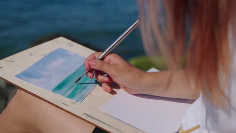 woman painting a seascape outdoors