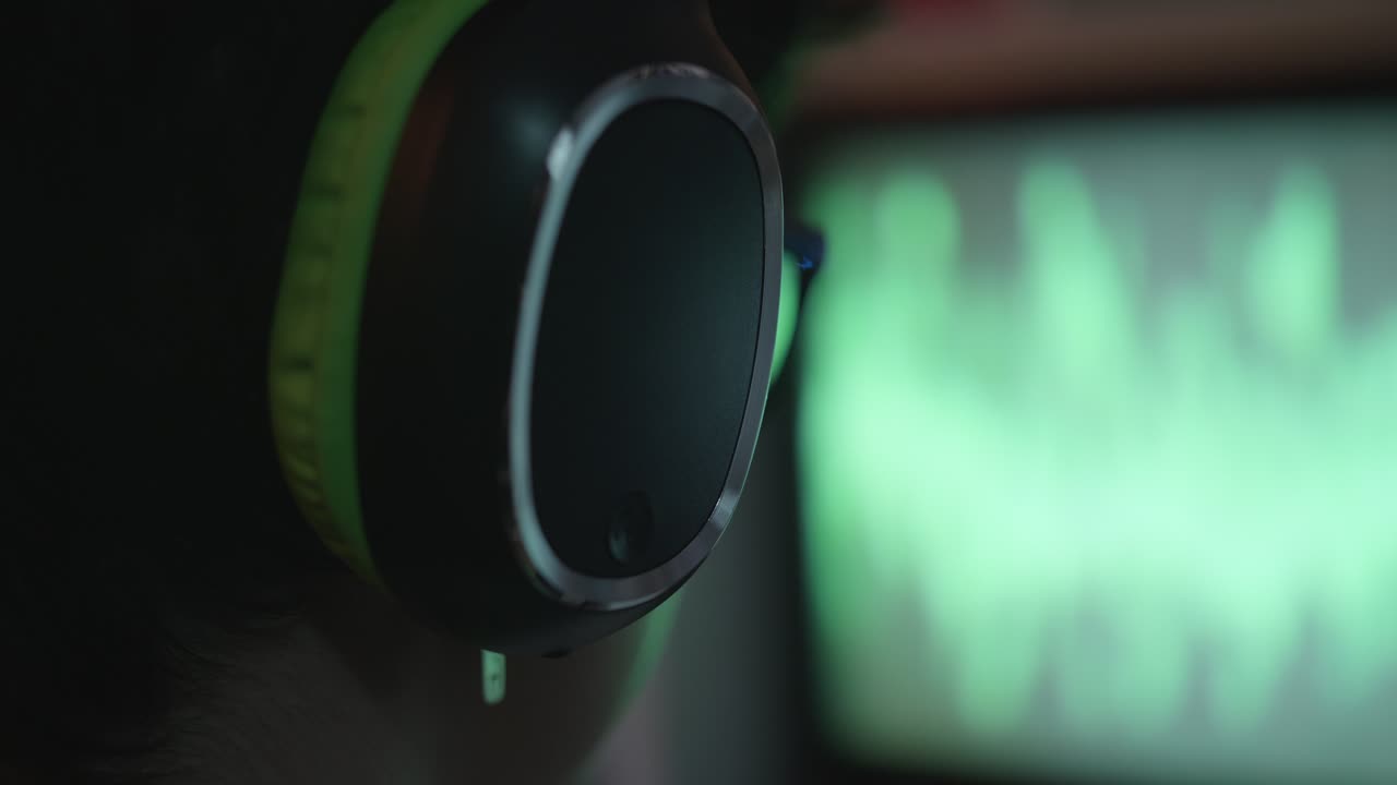 Close-up of Person Wearing Headphones with Audio Waveform on Screen