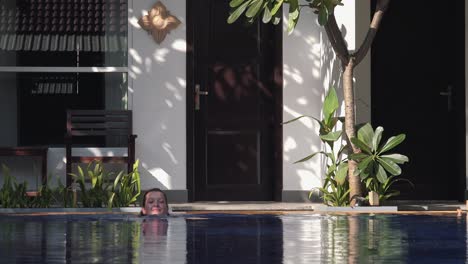 Wide-Shot-of-a-Young-Woman-in-a-Black-Bikini-Getting-into-Tropical-Hotel-Swimming-Pool