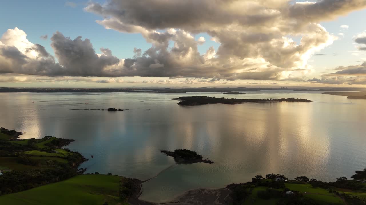 Waiheke island with sunset reflection over the water and isles nearby, aerial shot
