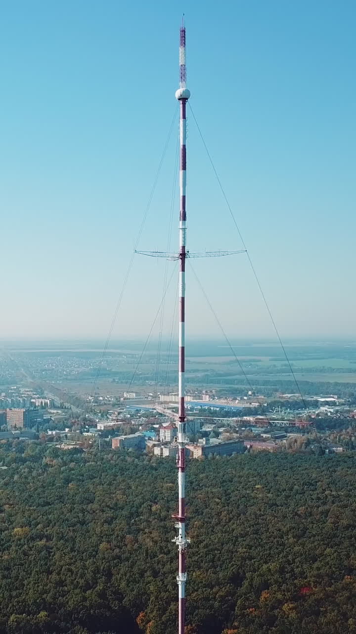 one telecommunication tower is located near the city in the background of the forest. Camera motion back Vertical video