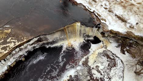 Vista-Aérea-De-Arriba-Hacia-Abajo-De-La-Cascada-Jägala-De-Estonia,-Río-Jägala,-Paisaje-Escénico-Blanco-Helado-De-Nieve-Invernal