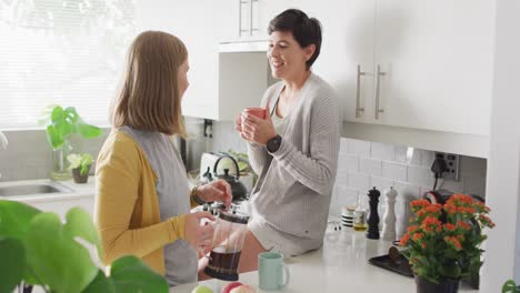 Caucasian-lesbian-couple-having-coffee-together-in-the-kitchen-at-home