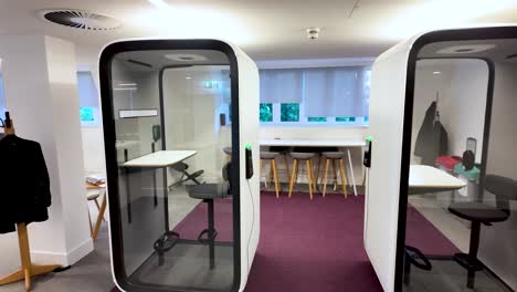 minimalist soundproof office pods providing a quiet and private workspace for employees needing concentration in a modern coworking space. pan left