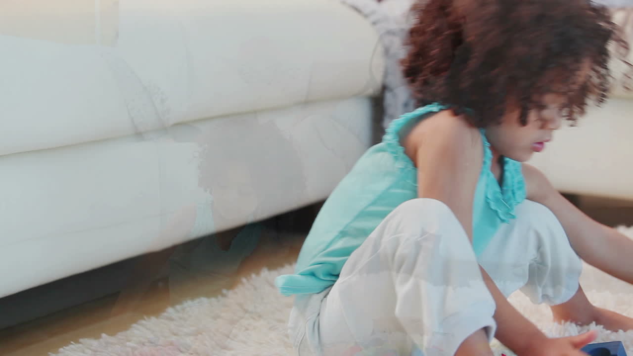 девочка играет с игрушечными блоками, в то время как ее родители сидят на диване.