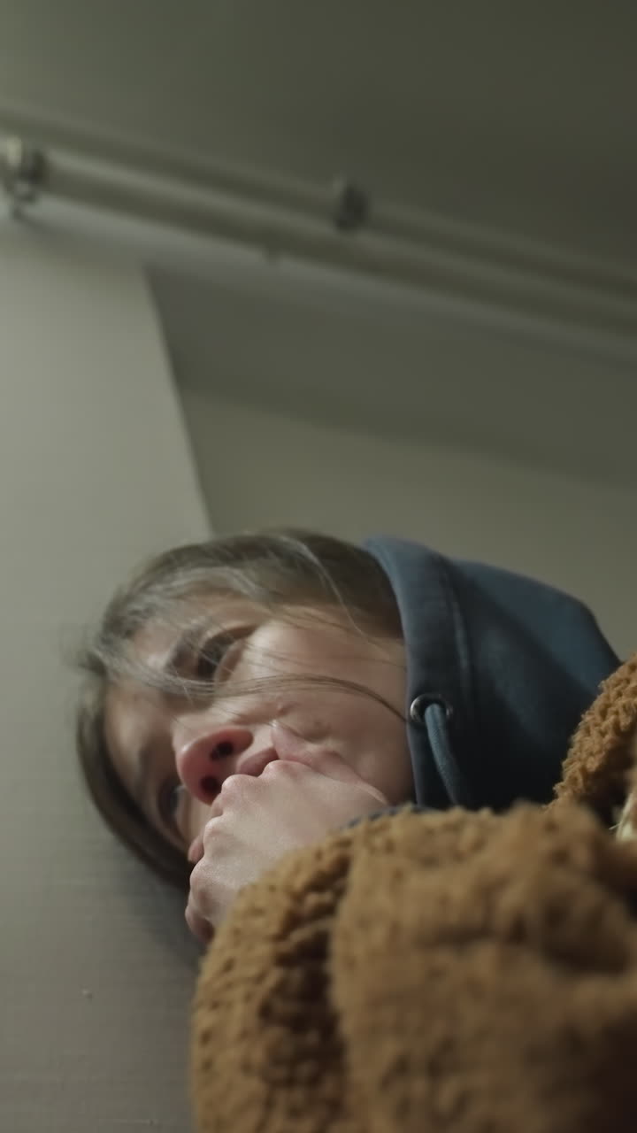 지하 통로의 벽에 기대어 눈물을 흘리는 소녀의 클로즈업, 그녀는 심하게 곤란해 보이며, 그녀의 손은 부분적으로 그녀의 얼굴을 고, 정서적 고통의 순간입니다.