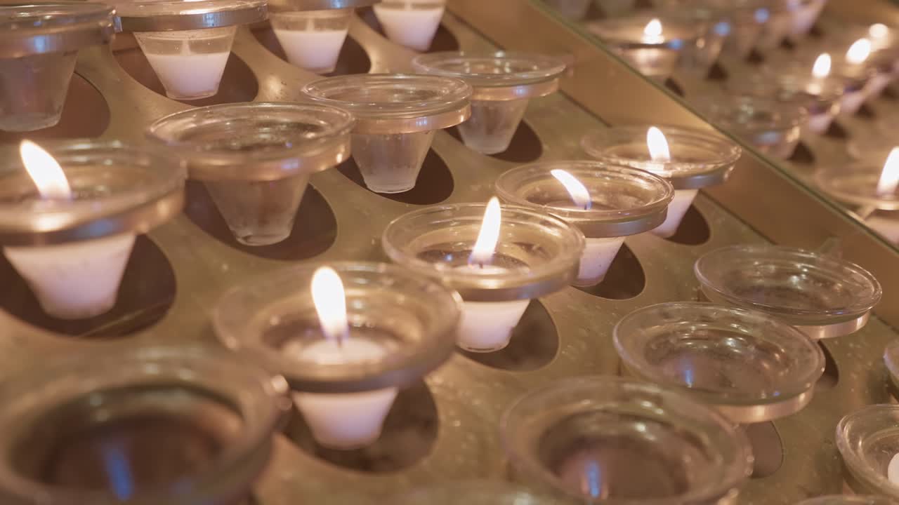 Крупный план зажженных молитвенных свечей, создающих спокойное духовное настроение