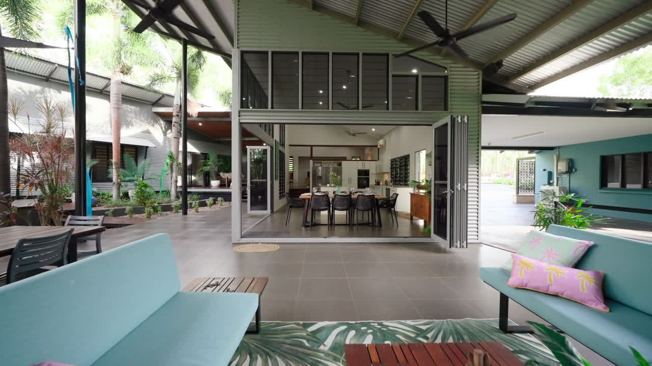 veranda de estilo tropical rural de prestígio através de área de estar de plano aberto completa com arte vibrante e cadeiras e bancos confortáveis
