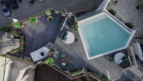 Hotel-rooftop-bar-and-swimming-pool-in-Riviera-Maya,-Mexico,-drop-down-aerial-view