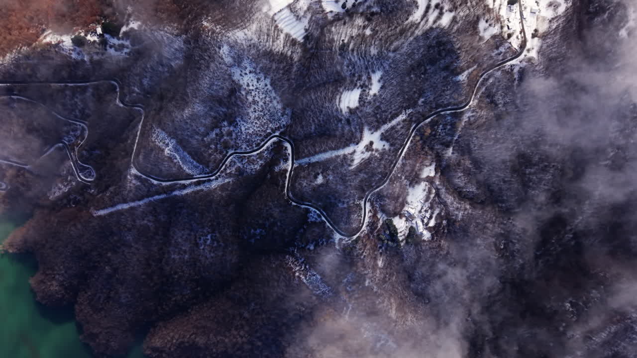 Aerial winter view of winding mountain road through snow and fog
