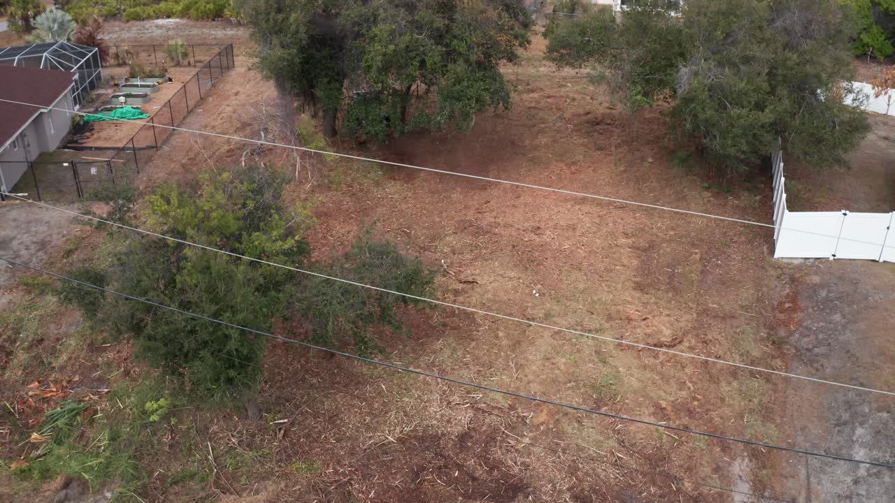 A residential lot being cleared, with trees and fencing surrounding the area. Useful for real estate development or landscaping projects