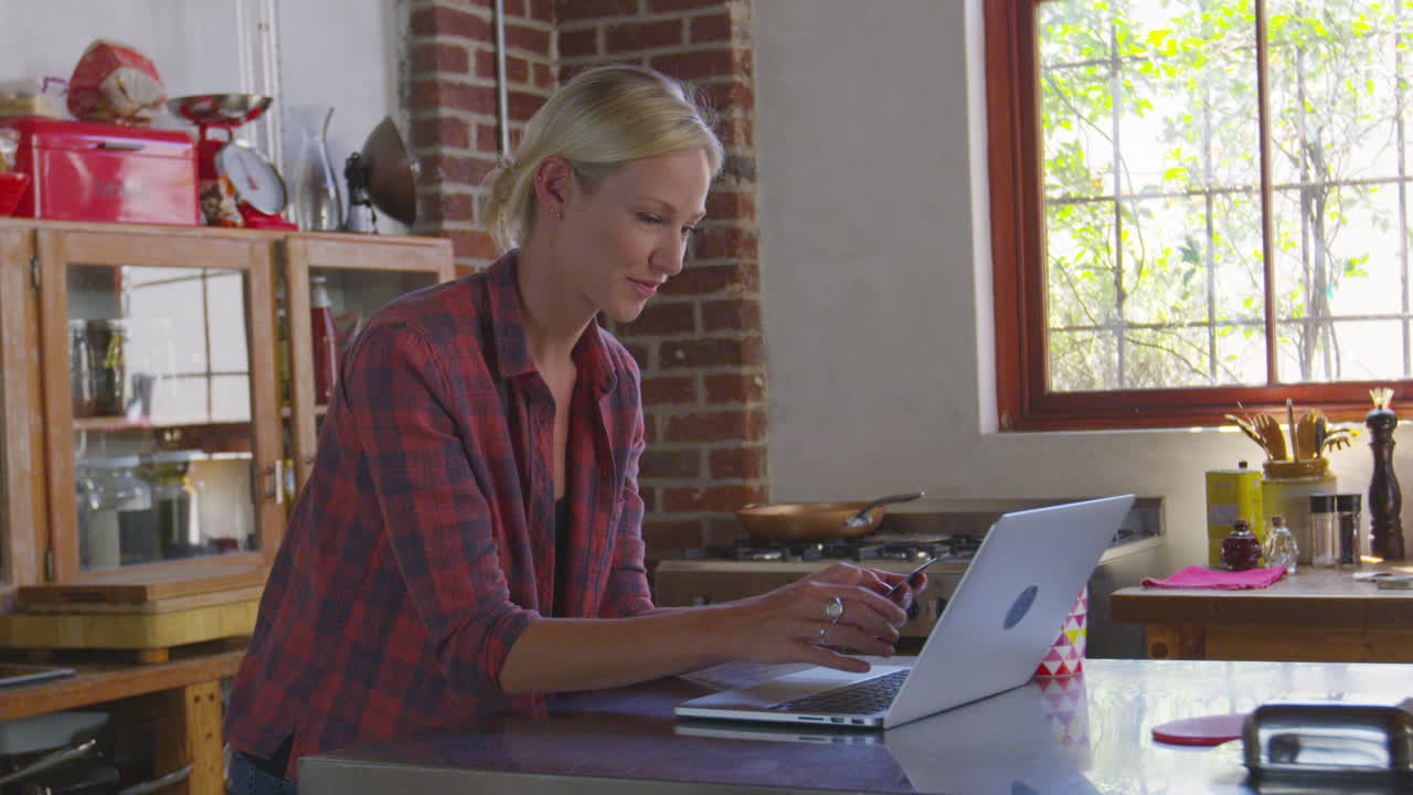 mujer joven comprando en línea en su cocina, cintura arriba, filmado en r3d