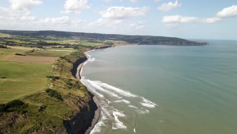 aerial drone footage of north yorkshire coastline,ravenscar with green fields and ocean