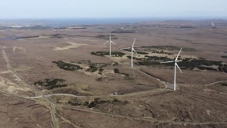 static drone shot of a wind farm with spinning wind turbines generating green, sustainable energy