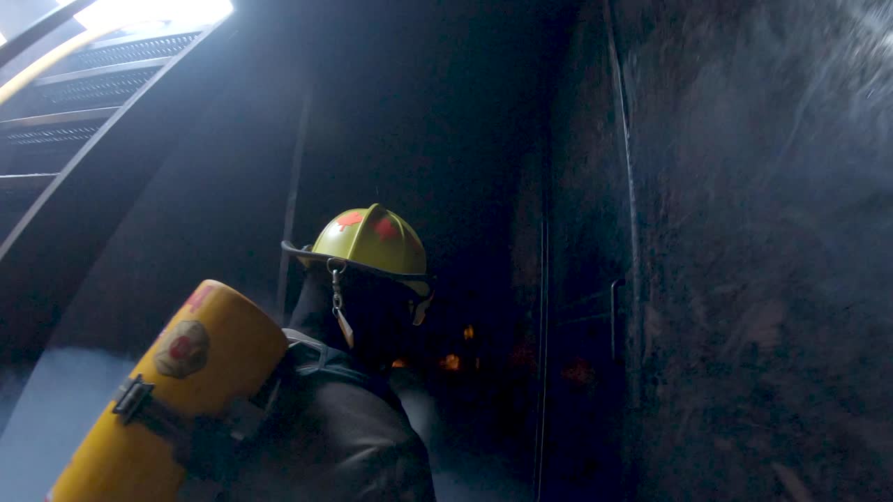 Firemen enter a simulator during training and begin to spay water on flames