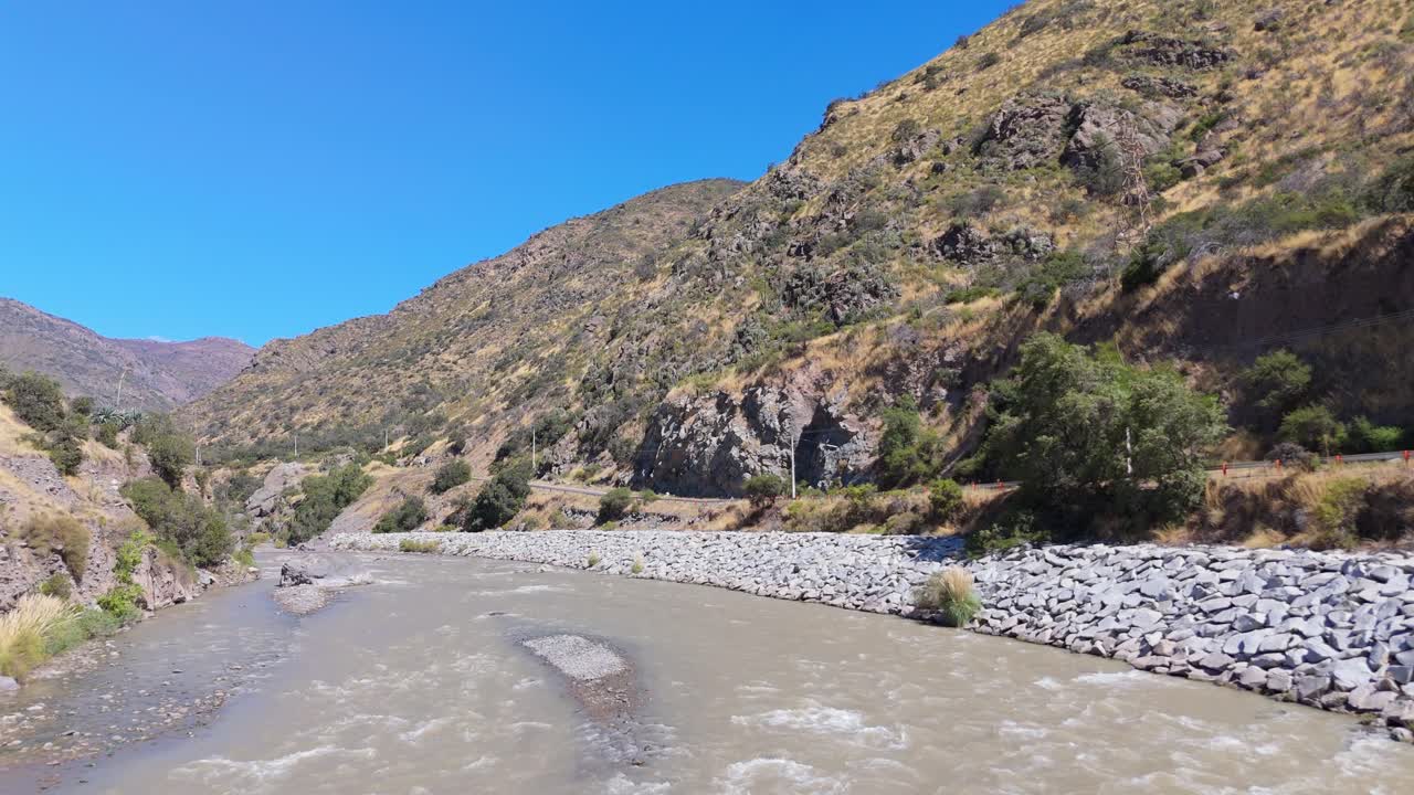 Fiume panoramico che scorre attraverso una valle di montagna arida sotto un cielo blu
