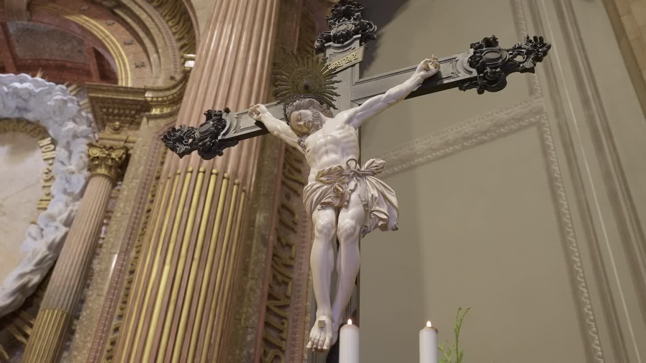 crucifix of Jesus Christ with golden halo above altar in Catholic church