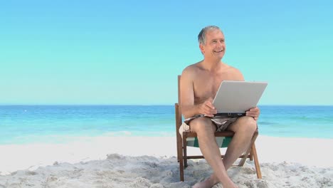 Älterer-Mann,-Der-Einen-Laptop-Benutzt-Und-Auf-Strandkörben-Sitzt