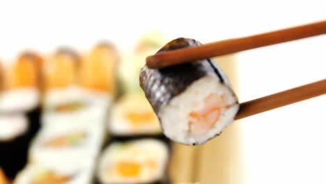 maki sushi siendo sostenido en palillos de madera