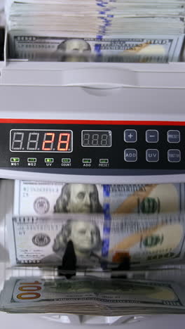 clerk hand counting dollars with electronic money counter machine at bank office or currency exchanger vertical video