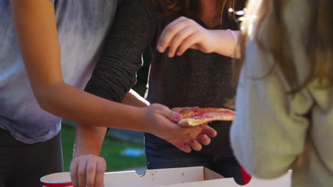 adolescentes compartiendo una pizza en una fiesta de bloque de vecindario