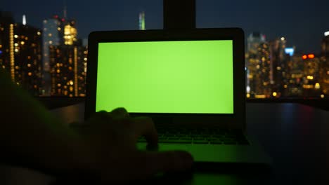 portátil de negocios con pantalla verde monitor de clave croma y fondo de paisaje urbano.