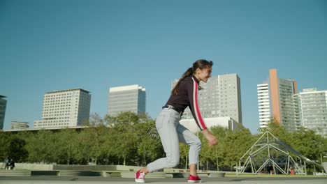 Empowered-Happy-Young-Attractive-Latin-Woman-does-an-energetic-jump-on-a-sunny-day-at-the-Barcelona-forum-city-wide-angle-shot