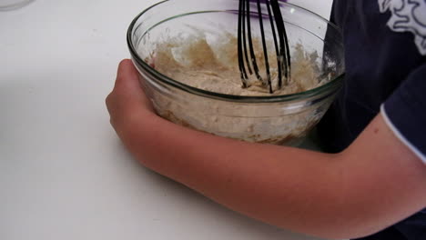 female hands slicing potato into thick cut fries on a wooden chopping board