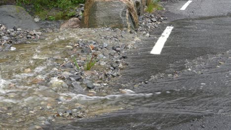 water from heavy rain runs off hill and flooding road in western norway