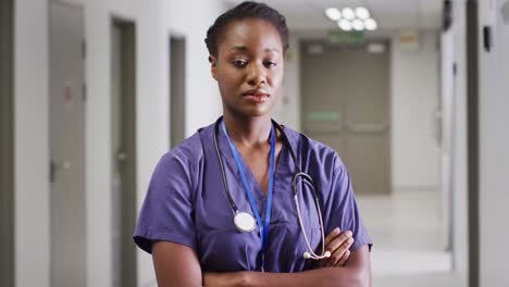 video portrait of serious african american female doctor standing in hospital corridor