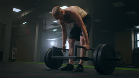 a tired man rests after lifting weights vilnay exercise deadlifts. preparing and adjusting concentration before training. mood and heavy breathing of an athlete with vapor in the gym