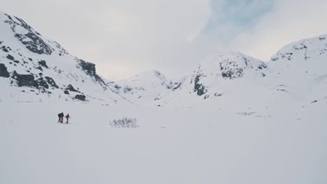 Couple-of-hikers-climbing-up-snowy-mountain-slope-in-Norway,-Vatnahalsen