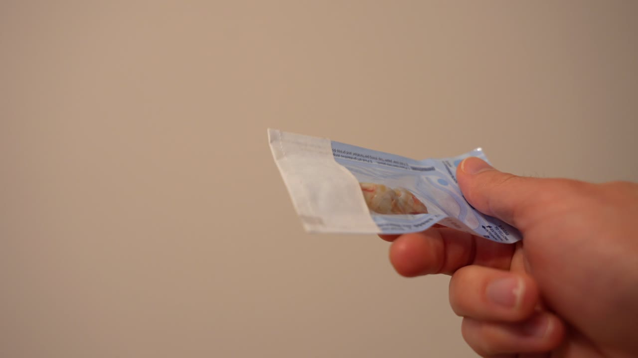 Nerozpoznatelný dospělý drží sáček s vytrženými zakrvavenými zuby moudrosti, detailní záběr