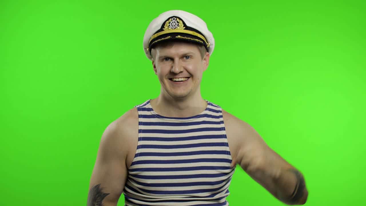 un joven marinero muestra una señal de ok, mirando a la cámara. un marinero en chaleco de marinero