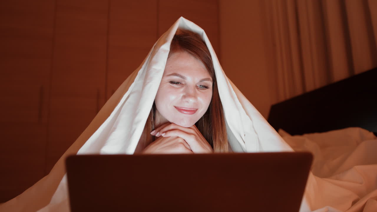 밤에 침대에서 노트북을 읽는 여자