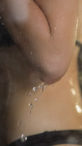 water jets wash slim young woman body skin behind transparent shower glass cabin reflecting daylight in early morning daily routine slow motion closeup