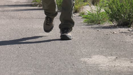 Man-in-hiking-boots-walking-up-track,-low-angle