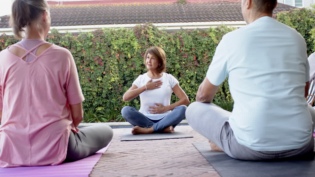 Ældre kvinde leder yogasession, guider venner i udendørs meditationspraksis