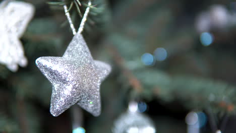 glittering silver star decor hanged on christmas tree with blurry background