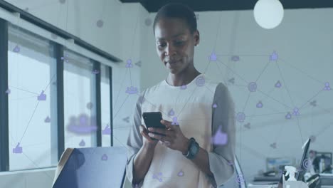 Animation-of-connected-icons-over-african-american-woman-using-cellphone-in-office