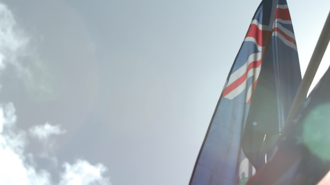 The Cayman Islands UK flag and U.S. flag blowing in the wind in slow-motion.