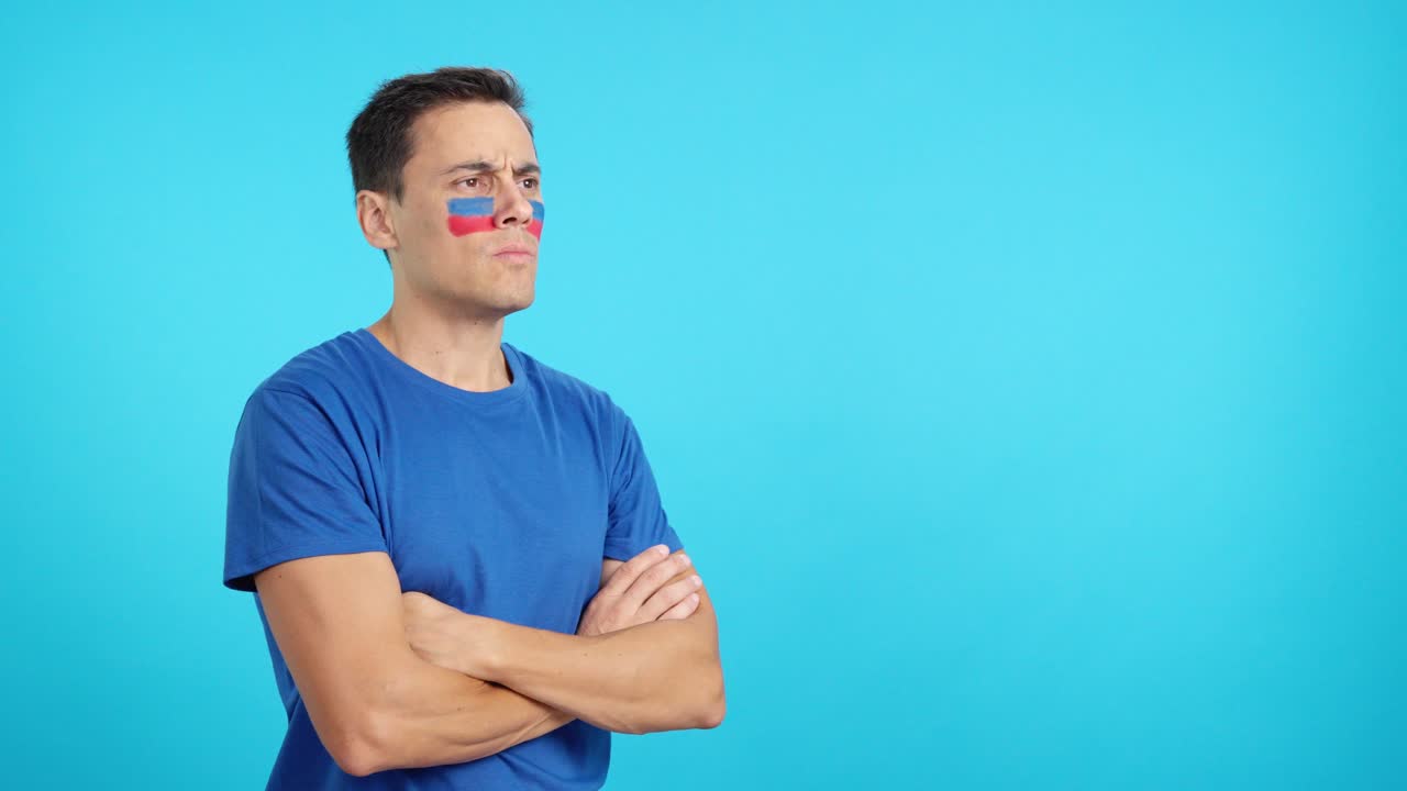Man with haitian flag painted looking away with serious expression