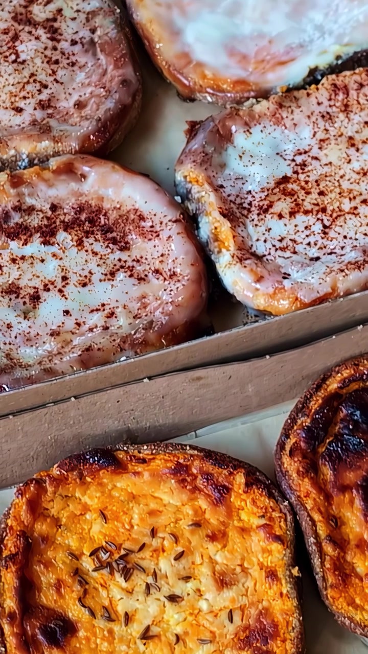 Assorted baked pastries with creamy icing and golden toasted cheese topping