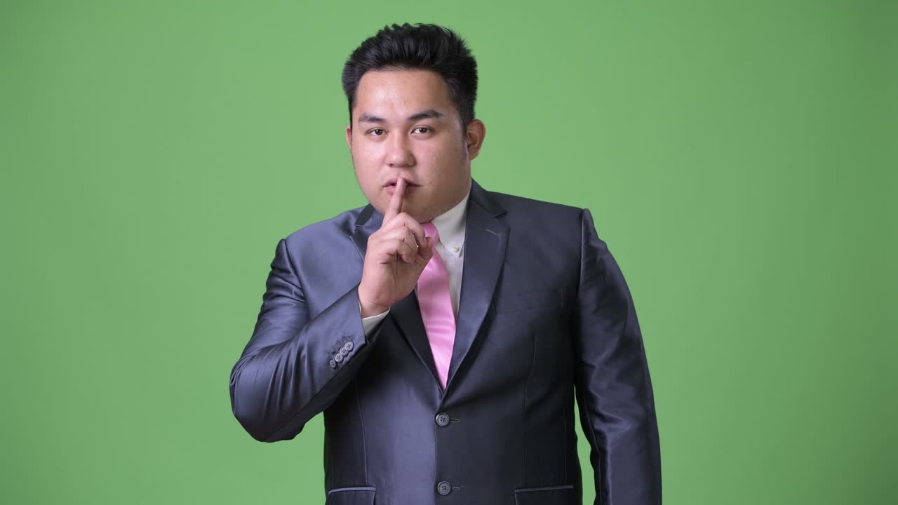 초록색 배경에 젊은 잘생긴 과체중 아시아 사업가