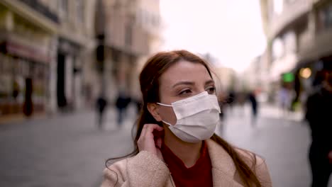 beautiful girl wearing protective medical mask and fashionable clothes stands at street