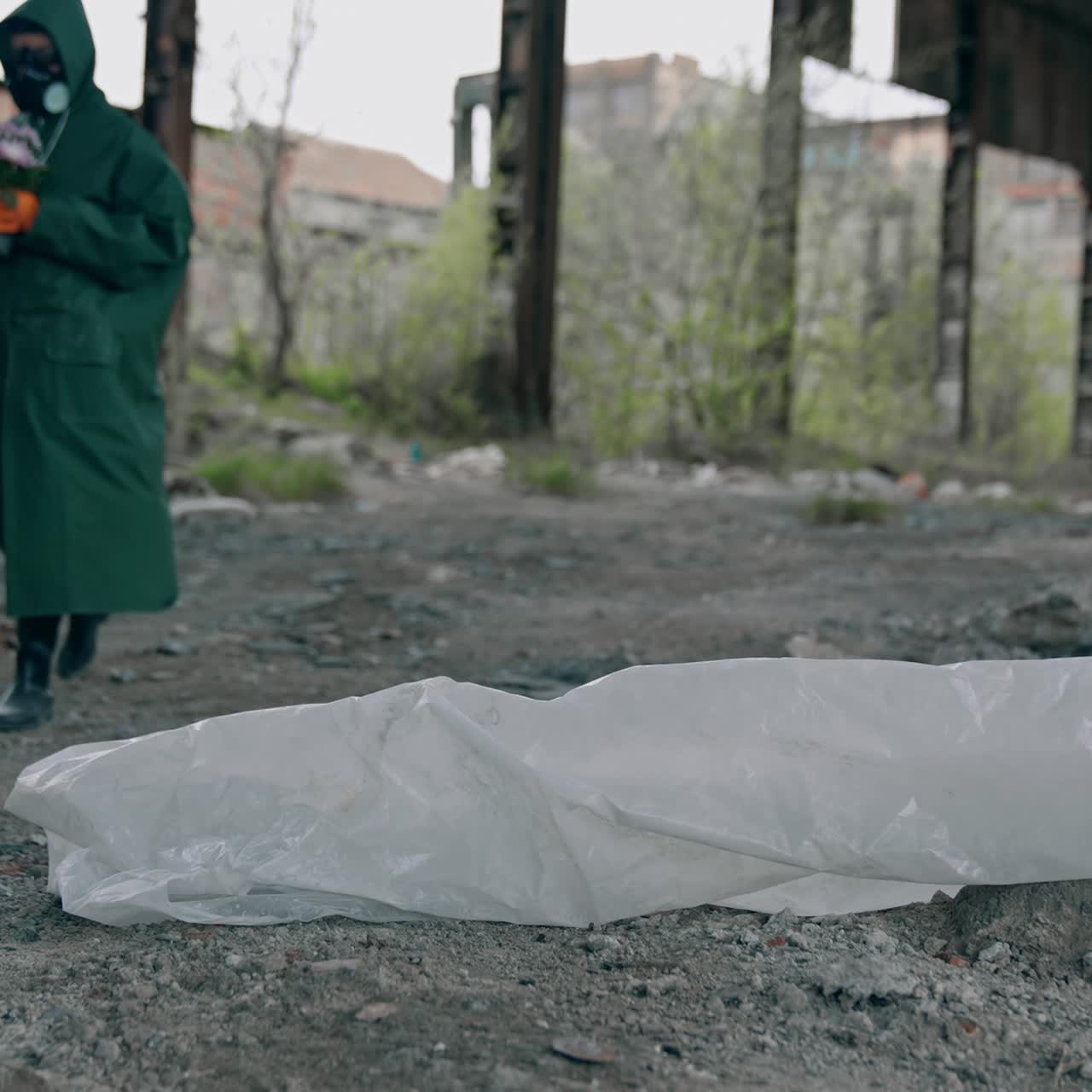 Human in protective suit in radioactive place. Man in safety costume and gas mask with flowers walking in abandoned place. Chemical attack. Pollution of the environment