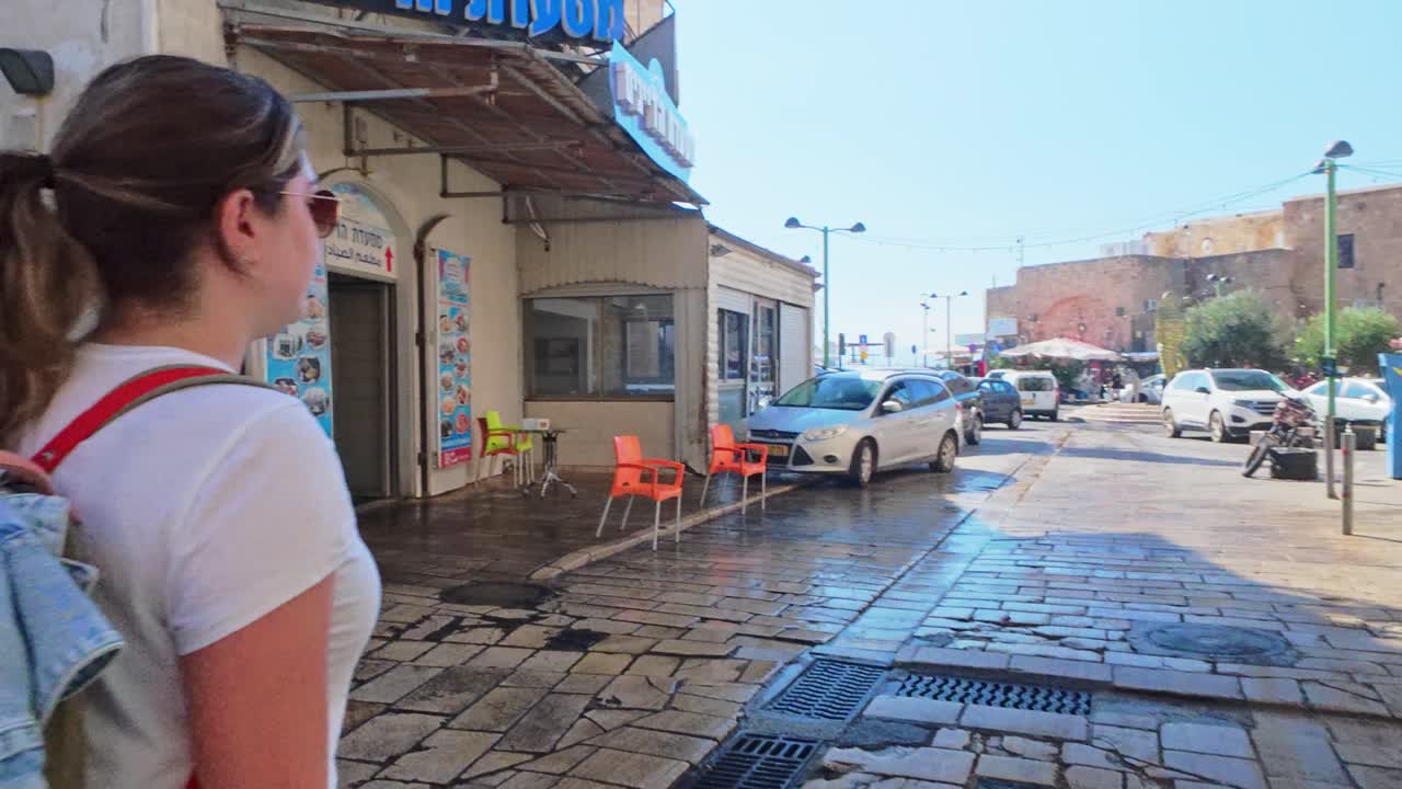 Rear view of female traveler walking down narrow historic alleyway