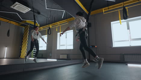 entrenamiento de suspensión en un club de fitness mujer deportiva adulta está haciendo saltos y saltos tensando los músculos de las piernas