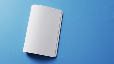 close up of open blank book with copy space on blue background in slow motion