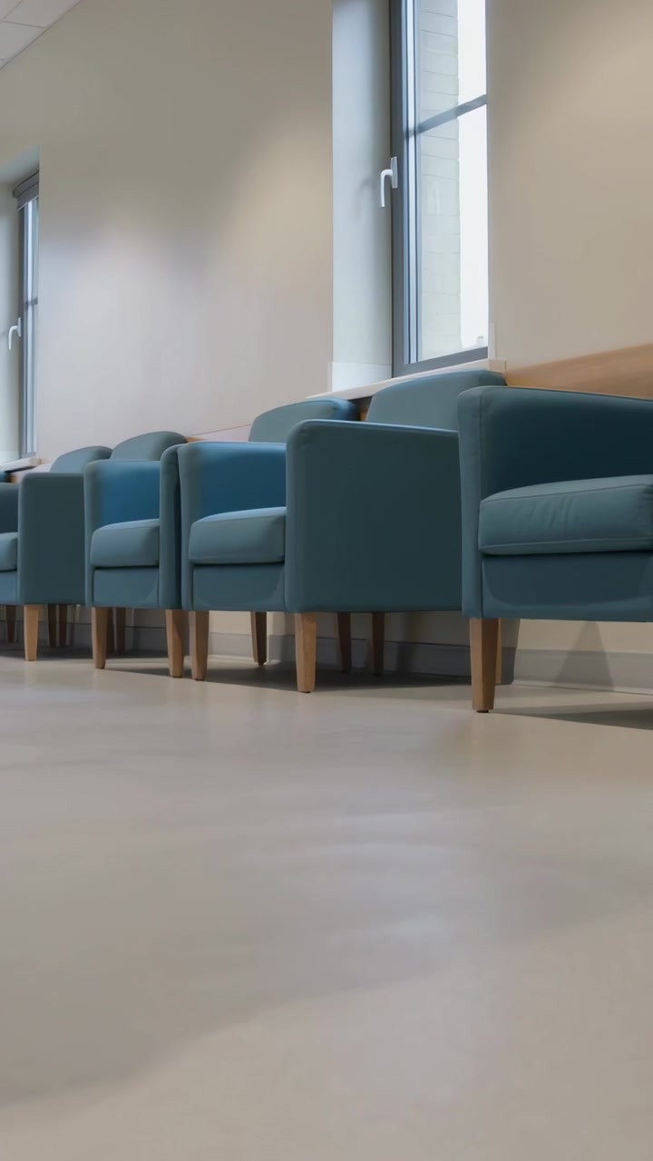 Vertical video: Panning low camera revealing teal armchairs aligned in waiting area, showing space